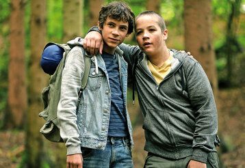 Zwei Jungen stehen Arm in Arm im Wald