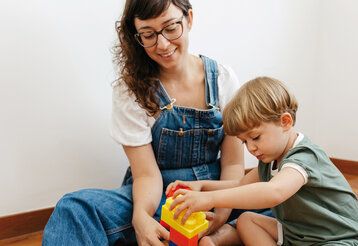 Mutter und Kind spielen mit bunten Bauklötzen